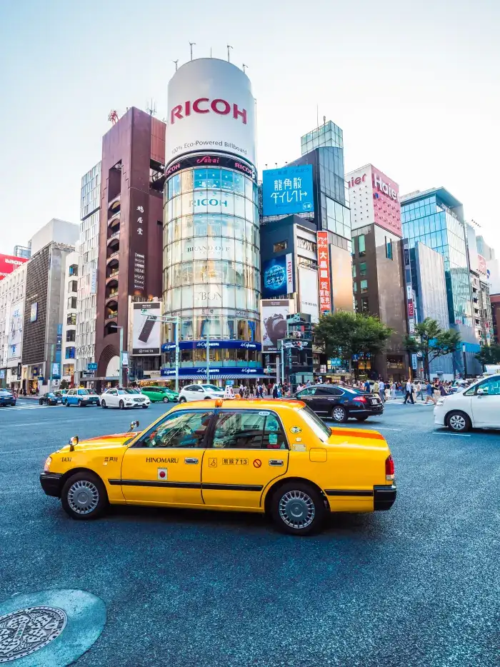 A taxi on a city street beneath tall buildings